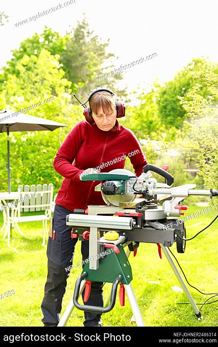 Woman using electric saw in garden