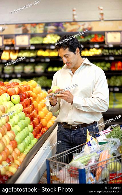 Man choosing apples from supermarket fruit stand