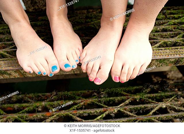 two sets of feet - teenage girls with painted toe-nails, UK
