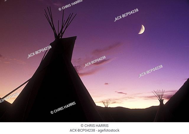 First Nations tee-pee village above the Fraser River at twilight with crescent moon, British Columbia, Canada