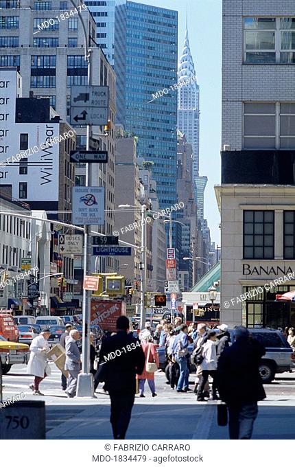 Passers-by walking on the busy commercial street Lexington Avenue. In the background, the Chrysler Building. New York, 1990s