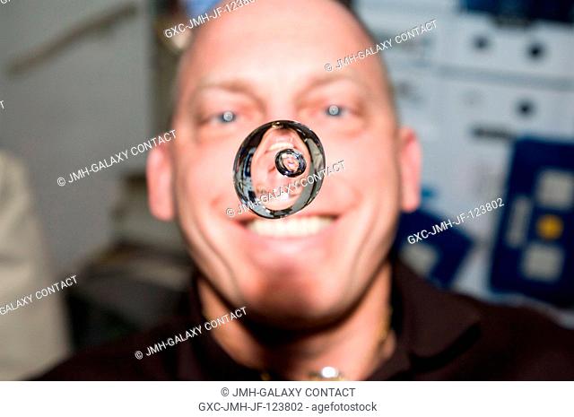 NASA astronaut Clayton Anderson, STS-131 mission specialist, watches a water bubble float freely between him and the camera, showing his image refracted