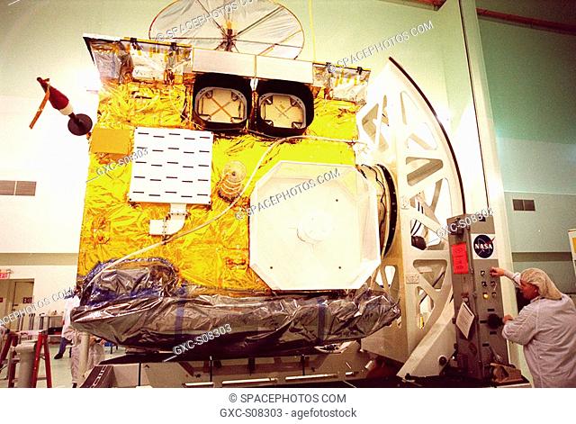04/12/2001 --- At Astrotech, Titusville, Fla., a worker right turns the GOES-M satellite, bringing its side into view. The GOES-M provides weather imagery and...