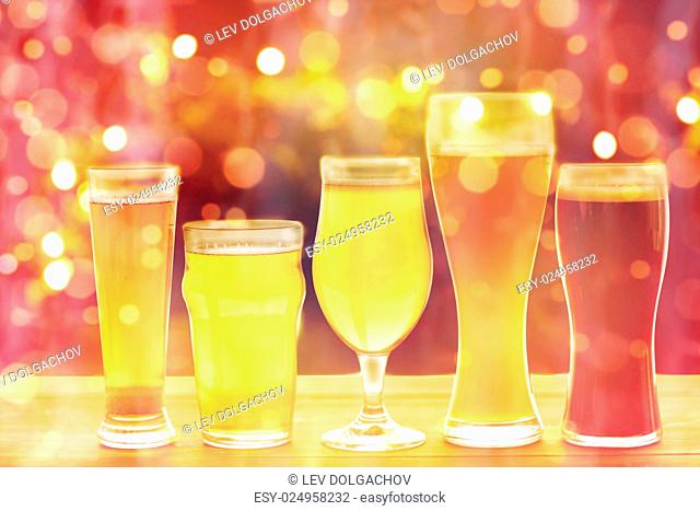brewery, drinks and alcohol concept - close up of different beers in glasses on table over holidays lights background