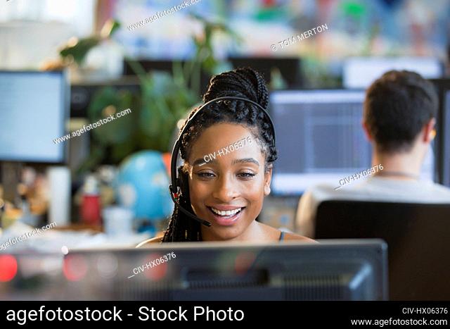 Smiling businesswoman with headset working at computer in office