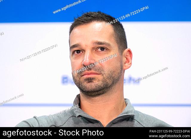 24 November 2023, Saxony, Dresden: Skeleton national coach Christian Baude stands on the podium during the press conference of the German Bobsleigh and Luge...