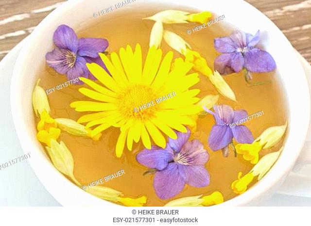 cough with coltsfoot, violet and primrose flowers in a white cup