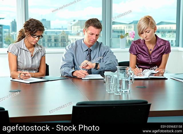 Panel of business people sitting at table in meeting room conducting job interview