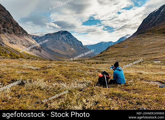 Rear view of hiker resting in mountains