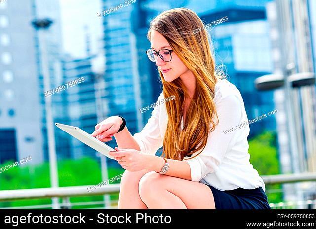 dynamic young executive girl working outside n a touchscreen tablet. Free of any constraint. Symbol of a job search or trade of outsourcing