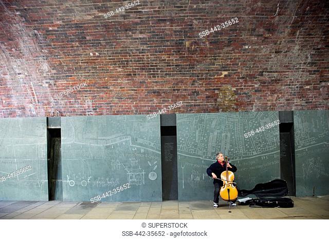 Street musician playing guitar under Southwark Bridge, South Bank, London, England