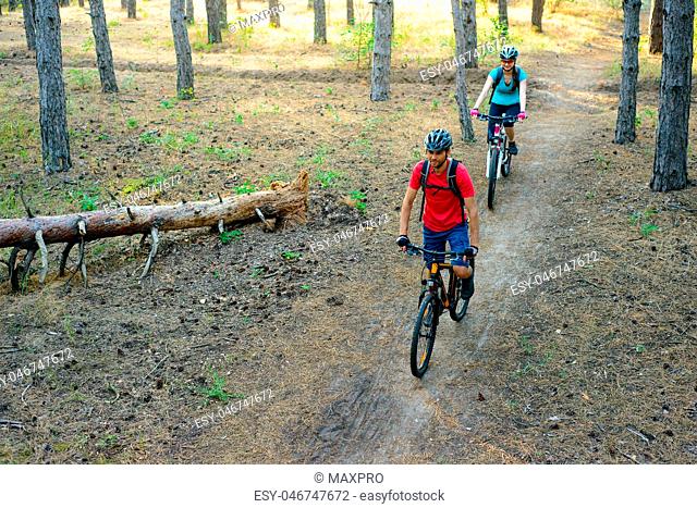 Young Couple Riding the Mountain Bikes in the Pine Forest. Adventure and Family Travel Concept