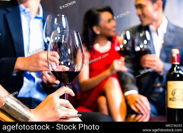 Close up of Asian friends chatting and drinking red wine