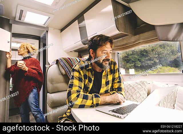 Adult couple travel and enjoy caming car camper van for holiday vacation or vanlife lifestyle - happy man work on laptop on the table and woman looking for...