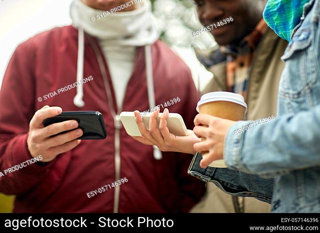 friends with smartphone and coffee outdoors