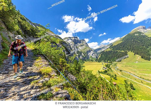 A hiker walks along the path called Scala Mola, Val Bargis valley, Flims, District of Imboden, Canton of Grisons (Graubunden), Switzerland, Europe