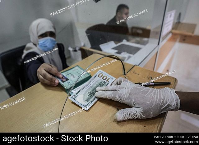 08 September 2020, Palestinian Territories, Gaza City: A Palestinian man receives a 100 US dollar bill at the post office in Gaza City as part of a Qatari aid...