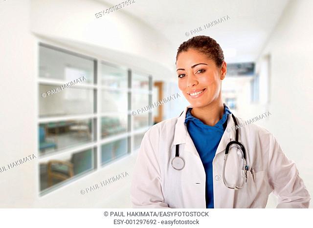 Beautiful attractive happy smiling female doctor physician nurse standing in hospital corridor hall way in front of patient consulting waiting area room