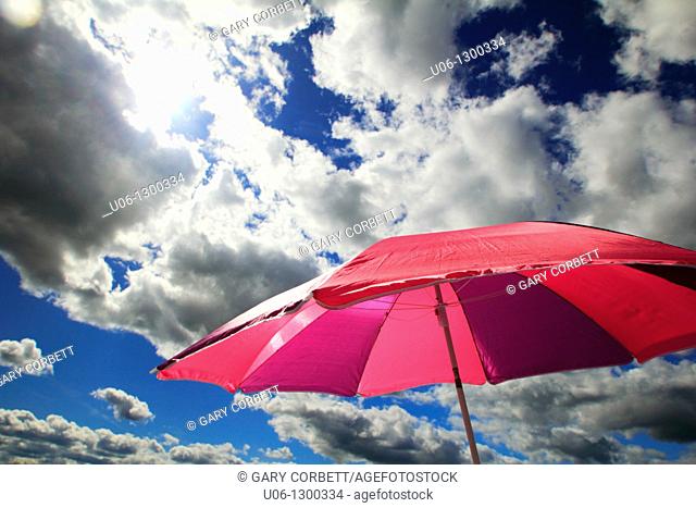 a beach umbrella with clouds and the sun
