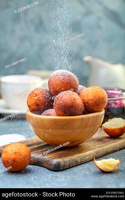 Delicious cottage cheese donuts in a wooden bowl sprinkle with powdered sugar, selective focus