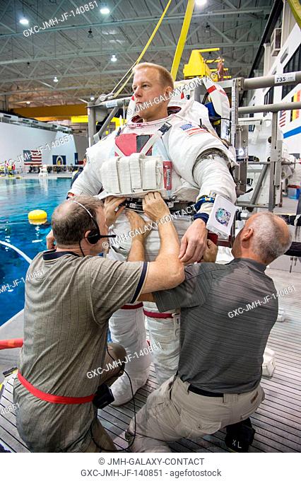 NASA astronaut Tim Kopra, Expedition 46 flight engineer and Expedition 47 commander, gets help donning a training version of his Extravehicular Mobility Unit...