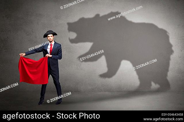 Businessman standing with red cloth in his hand and big bear shadow on his background