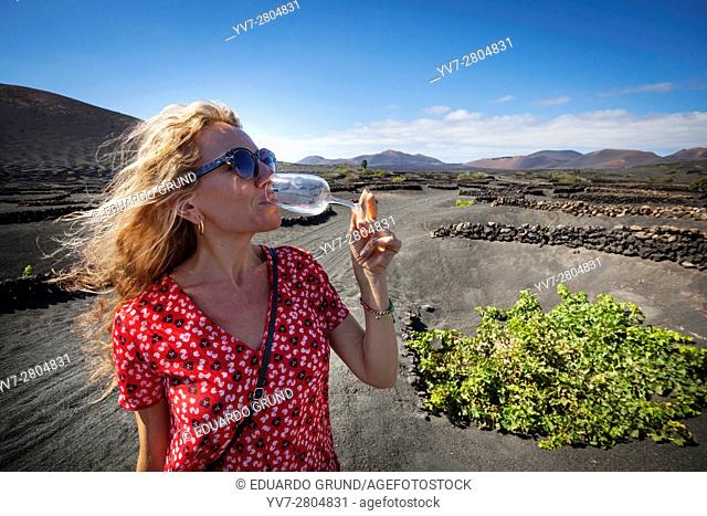 Wine tasting of the grape 'Volcanic Malvasia' on the ground surrounded by the traditional crops on the lava cones. Lanzarote islands, Las Palmas, Canary, Spain