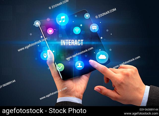 Businessman holding a foldable smartphone with INTERACT inscription, social media concept