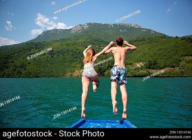 Young couple jumping on the edge of a boat