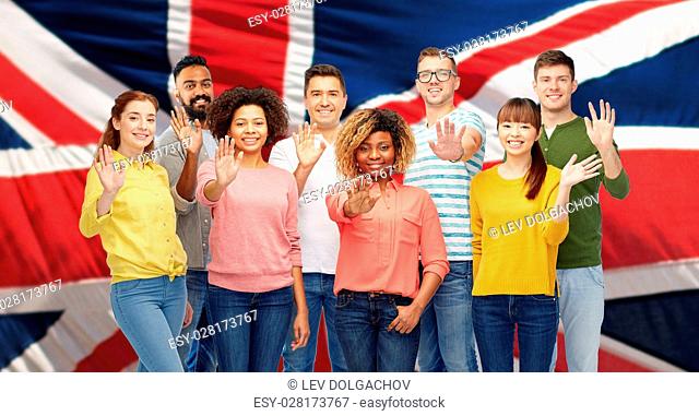 diversity, race, ethnicity and people concept - international group of happy smiling men and women waving hand over english flag background