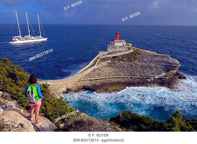 female hiker looking at the lighthouse Madonetta in the south of Corsica island, France, Corsica, Bonifacio