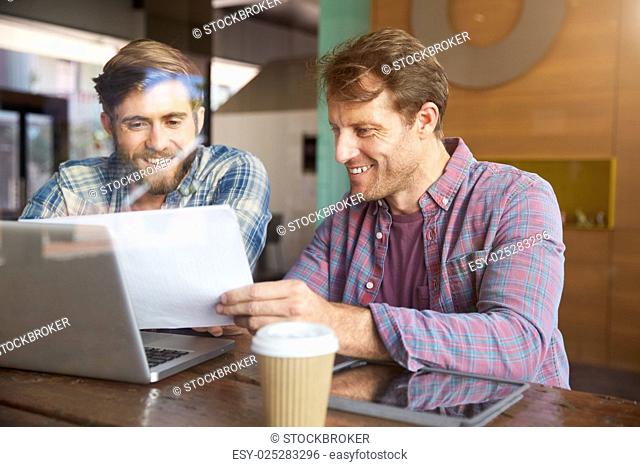 Two Businessmen Working On Laptop In Coffee Shop
