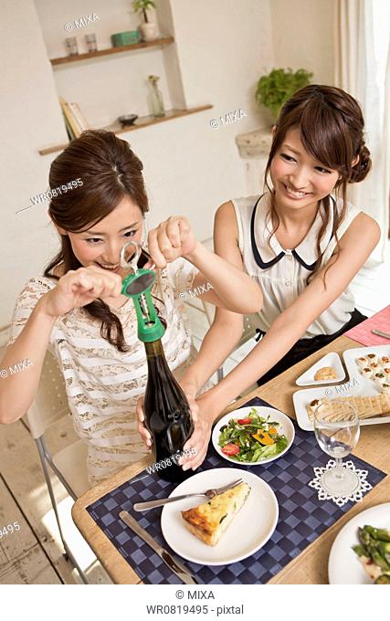 Two Young Women Opening a Wine Bottle
