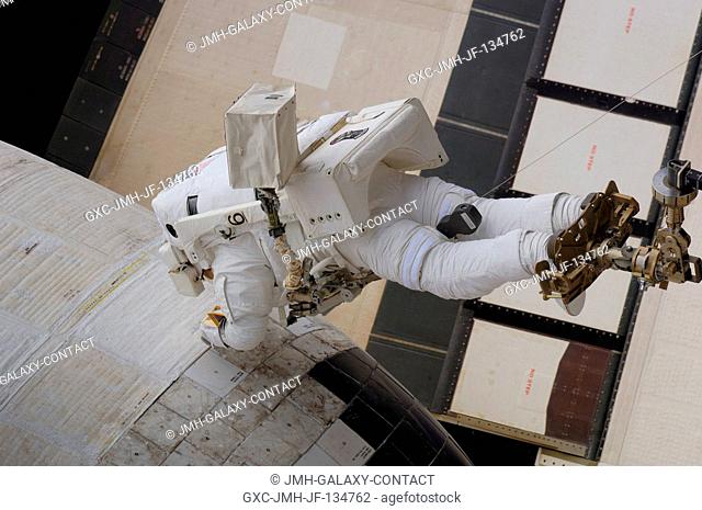 Anchored to a foot restraint on Space Shuttle Atlantis' remote manipulator system (RMS) robotic arm, astronaut John Danny Olivas, STS-117 mission specialist