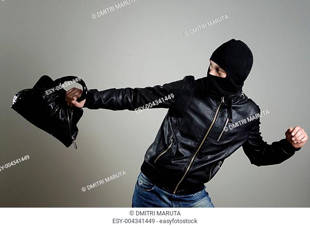 Portrait of running male burglar with a handbag