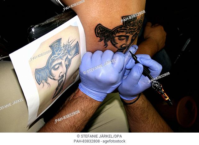 A client gets a Christ on the Cross tattoo on his upper arm at the Pain Art  tattoo studio in the old..., Stock Photo, Picture And Rights Managed Image.  Pic. PAH-83832808 |
