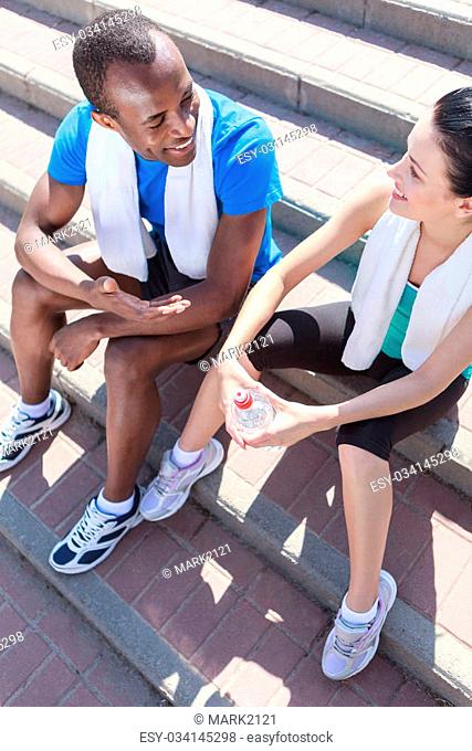 After the training. Young interracial couple sitting at stairs and talking after the training