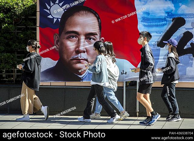 Passersby walk by an image of Sun Yat-sen - Chinese politician and revolutionary, leader and founder of the Kuomintang, Considered the founder of modern and...