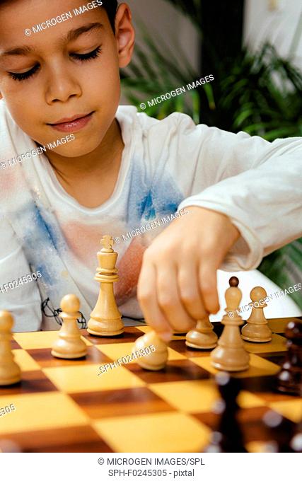 Boy playing chess at home. Sitting at the table and thinking hard