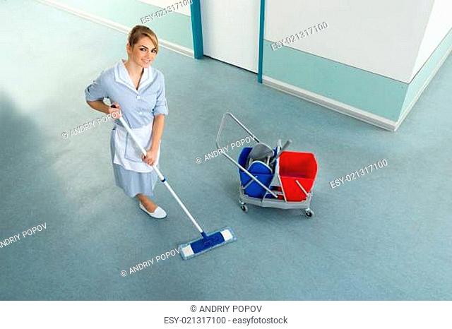 Happy Female Janitor With Mop And Cleaning Equipment On Floor