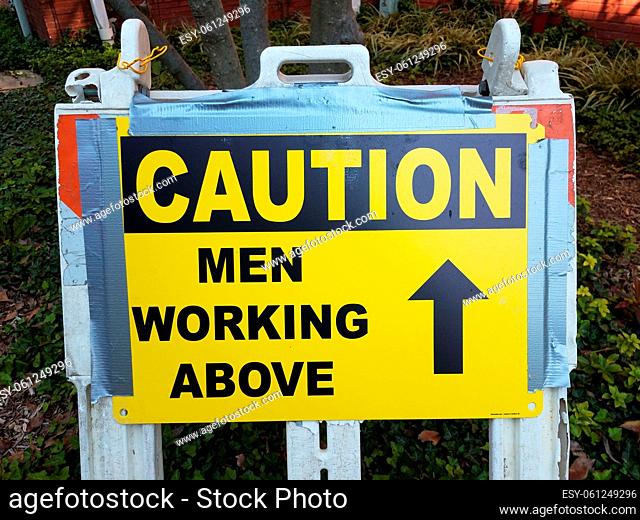 yellow caution men working above sign with arrow