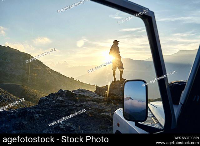 Tourist standing on rock at sunset, Colle dell'Assietta, Turin, Italy