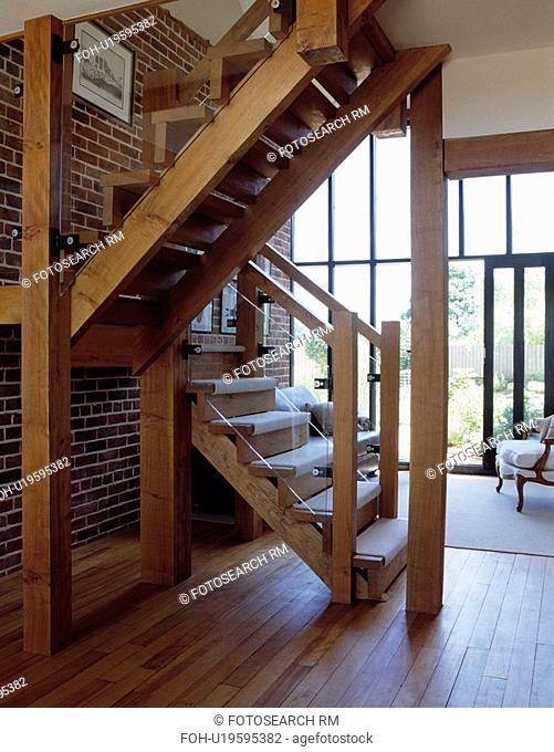 Wooden staircase in hall with wooden flooring in barn conversion with white rug