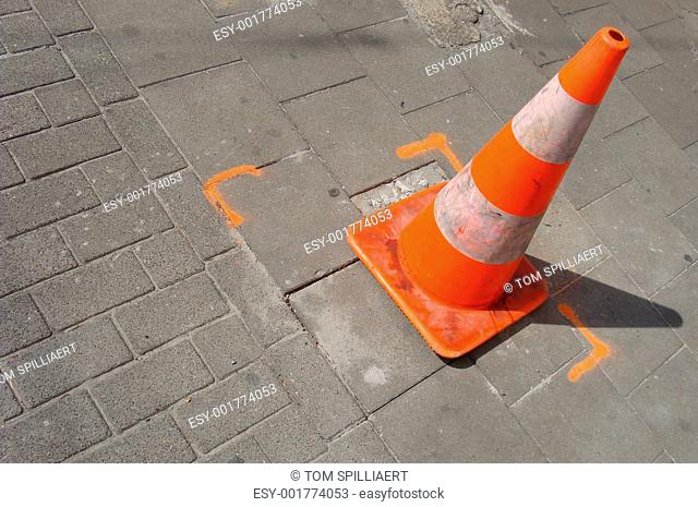 typical orange and white traffic cone standing on pavement