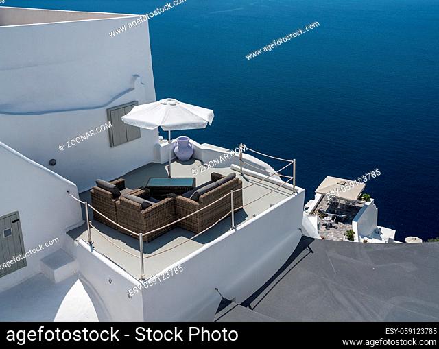 Patio furniture on deck above blue ocean in Santorini