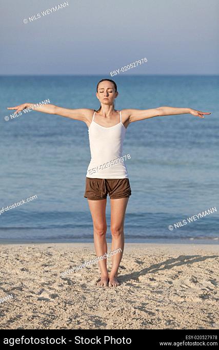 Frau macht yoga Sport am Strand Hochformat
