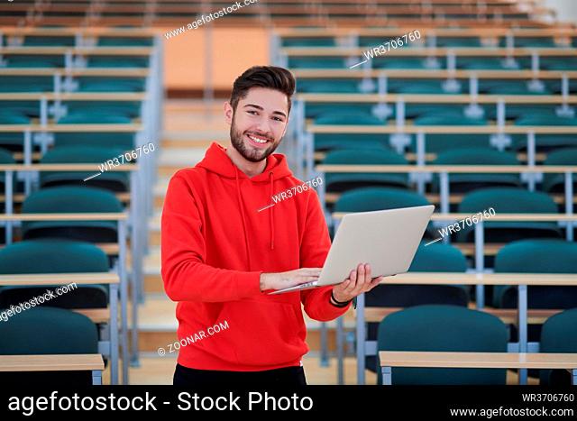 Man student working on laptop in college classroom