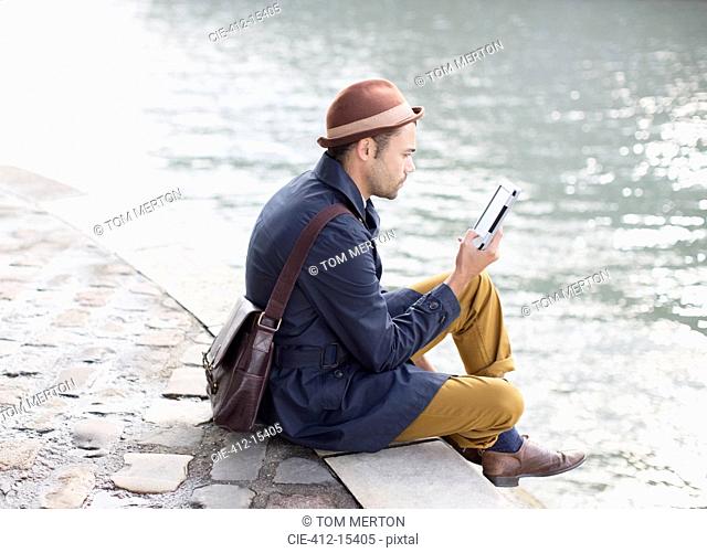 Man using digital tablet along river