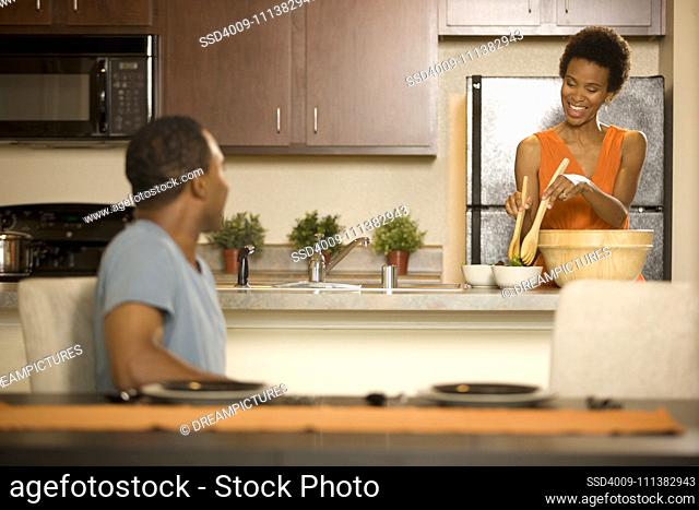 Woman in kitchen making salad with man