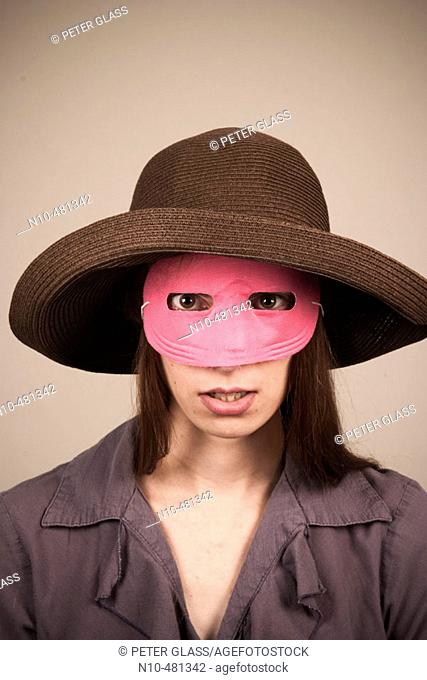 Young woman, wearing a hat and pink mask, posing
